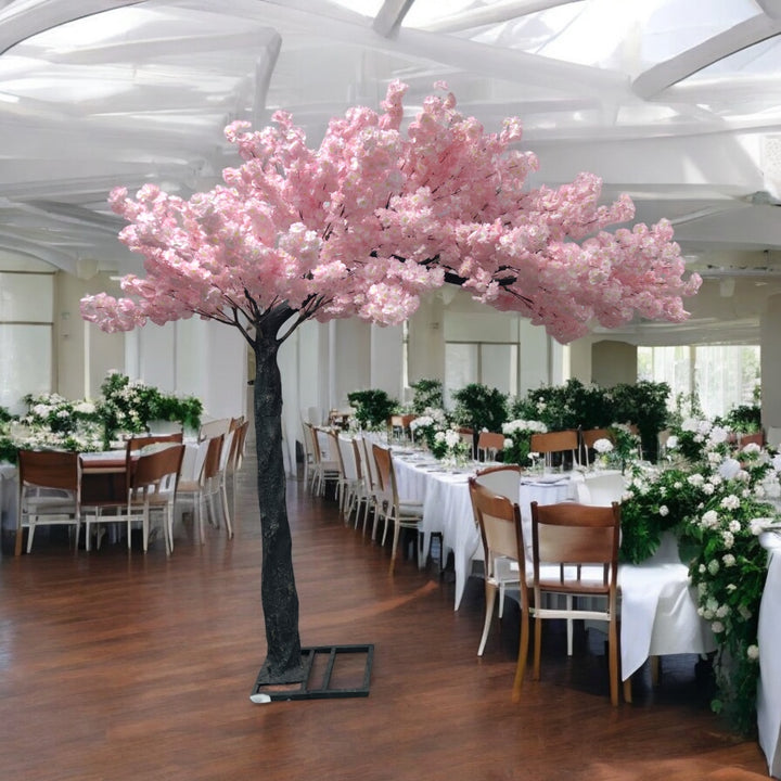 Artificial cherry blossom tree with pink flowers, perfectly placed amidst a lavishly decorated wedding venue featuring pink floral arrangements and cascading fairy lights. Can this artificial tree be customized to match different event themes?