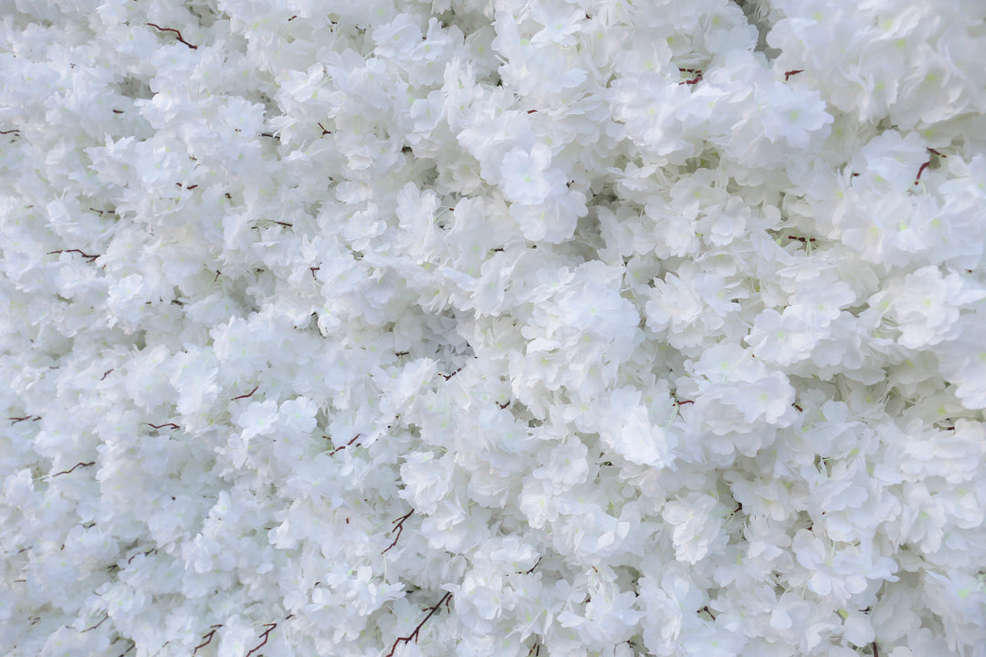 Close-up of a white artificial flower wall backdrop with delicate layered petals, ideal for weddings, events, or photoshoots. 
How durable is the material for prolonged events? Can the flower wall be customized in color or size? Is it suitable for both indoor and outdoor use?