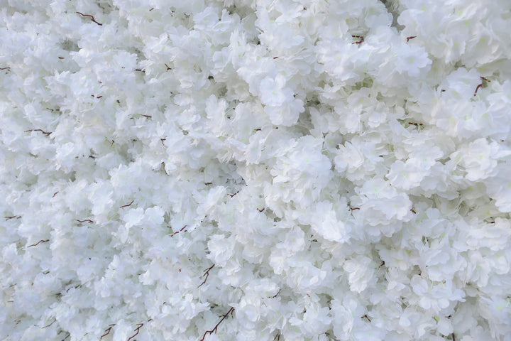 Close-up of a white artificial flower wall backdrop with delicate layered petals, ideal for weddings, events, or photoshoots. 
How durable is the material for prolonged events? Can the flower wall be customized in color or size? Is it suitable for both indoor and outdoor use?