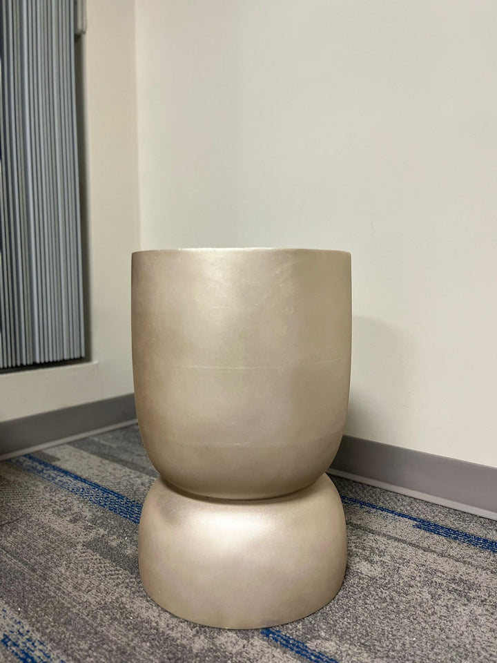 Gold stackable planter with a smooth metallic finish, displayed empty indoors on a carpeted floor near a window. Is this planter suitable for modern minimalist decor?