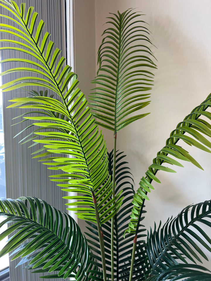 Close-up of artificial palm fronds, showcasing vibrant green leaves and realistic detailing, ideal for indoor decoration.