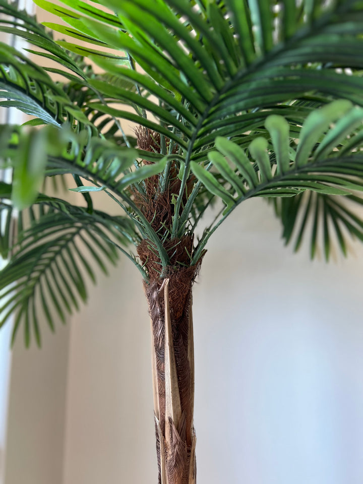 Artificial palm tree with detailed close-up of lush green fronds and a realistic trunk base, perfect for home or office decoration