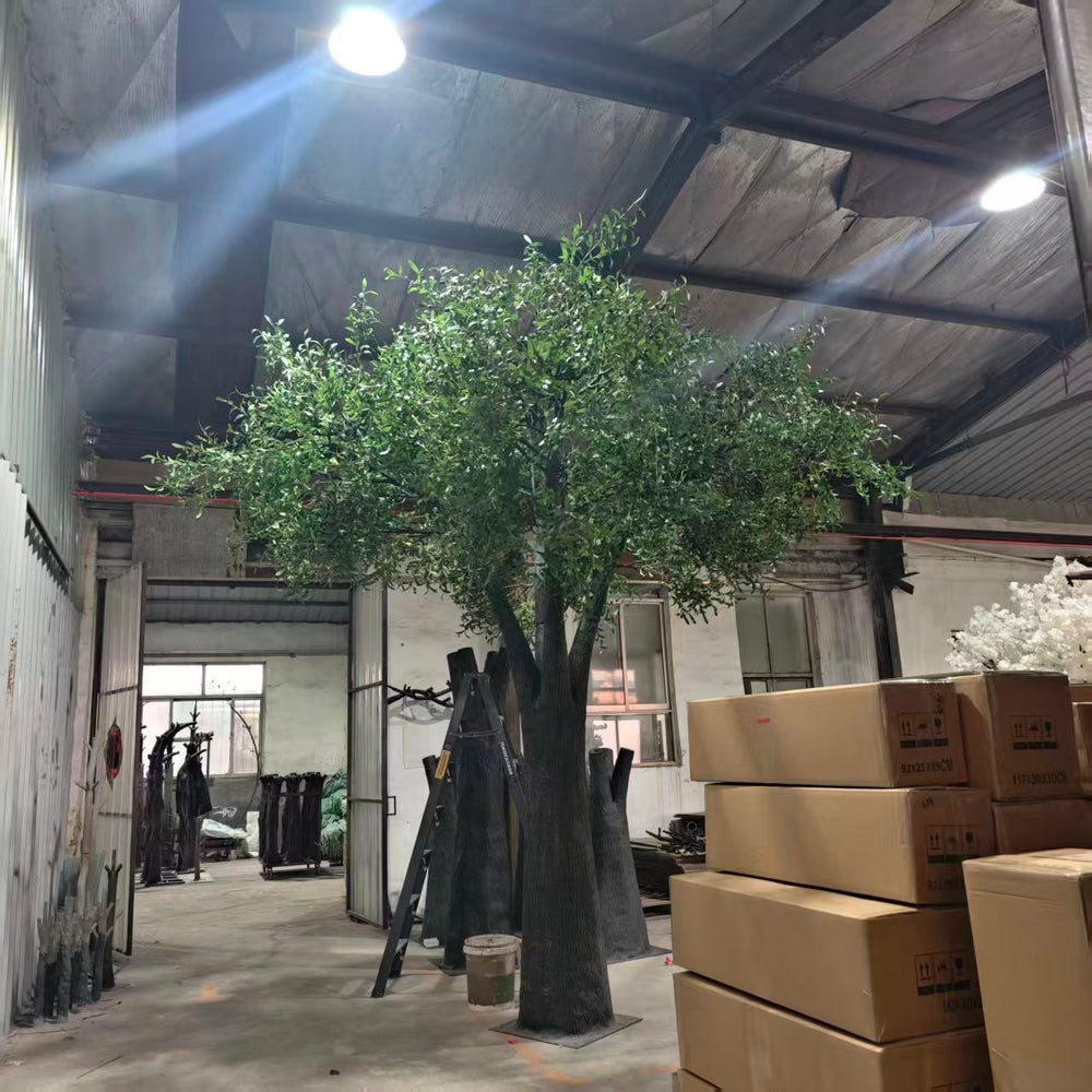 15ft Artificial olive tree in a warehouse setting with boxes and equipment.