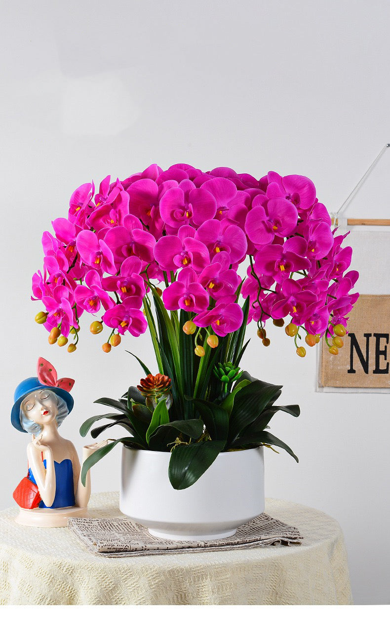 A vibrant artificial orchid arrangement in a bright fuchsia color, displayed in a modern white planter. Frequently asked question: How do I maintain artificial orchids to keep them looking fresh and dust-free?
