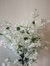 Load image into Gallery viewer, Close-up of an artificial white flower tree with delicate blossoms and green leaves, placed against a neutral-colored wall.
