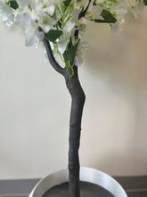 Load image into Gallery viewer, Close-up of the trunk and base of an artificial white flower tree, showing the dark, textured stem placed in a white round planter
