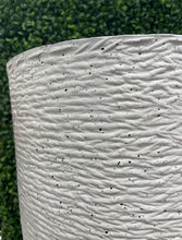 Load image into Gallery viewer, Close-up of a textured white planter with black speckles, showcasing the intricate surface design against a green artificial plant backdrop. Frequently asked questions: What materials are best for durable outdoor planters? How do textured planters complement modern interior designs? Are textured planters suitable for both artificial and live plants?
