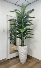 Load image into Gallery viewer, A large artificial palm plant in a white planter with a scale-like texture, placed indoors next to a door with a mirror. The plant adds a tropical touch to the modern interior setting.
