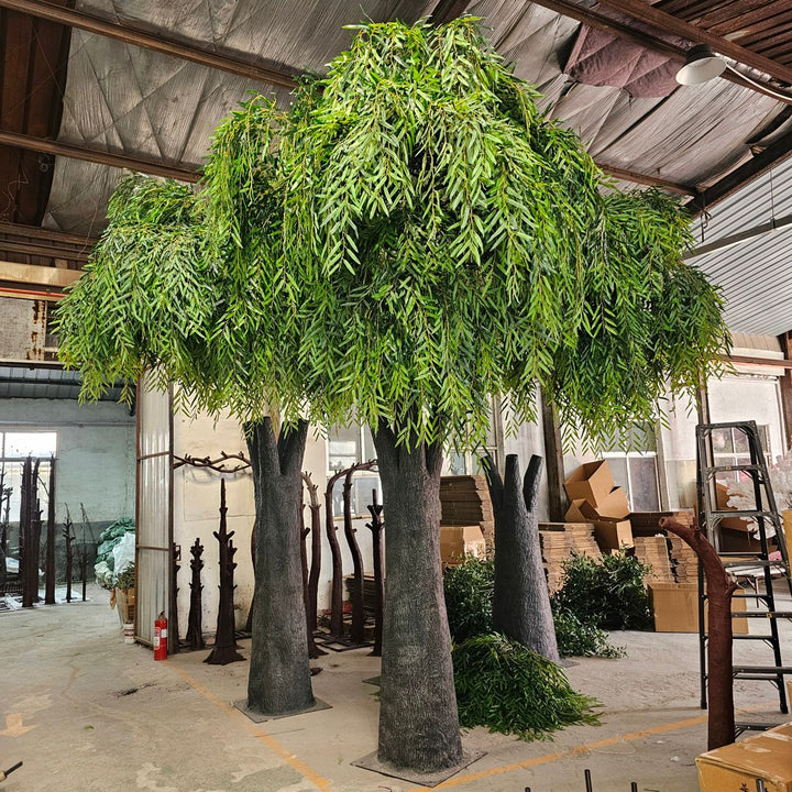 Large artificial willow tree in a warehouse setting with boxes and equipment in the background