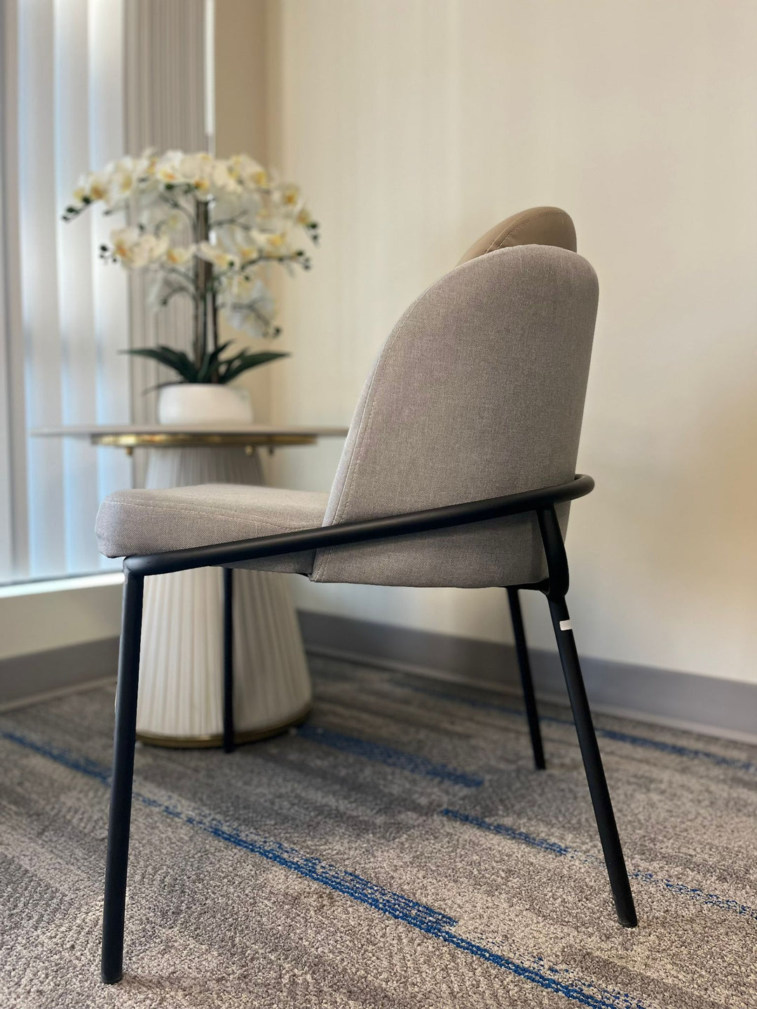 Side view of a modern gray upholstered chair with a sleek black metal frame, ideal for minimalist or contemporary home designs. This chair is commonly sought after for its comfort and elegant aesthetic, often searched with questions like ‘What are the best ergonomic chairs for modern spaces?