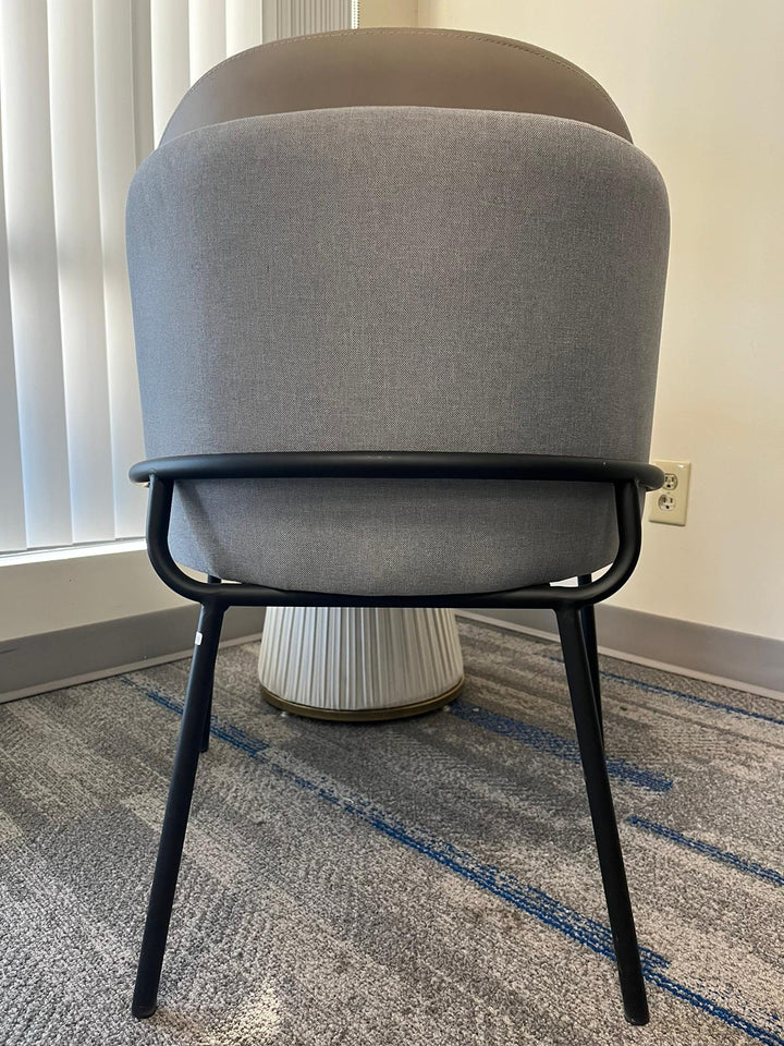 Back view of a modern gray upholstered chair with a black metal frame, often chosen for its contemporary style and comfort. Frequently asked questions about this chair include ‘What are the best chairs for lumbar support in small spaces?’ and ‘How do modern chairs enhance home office setups?