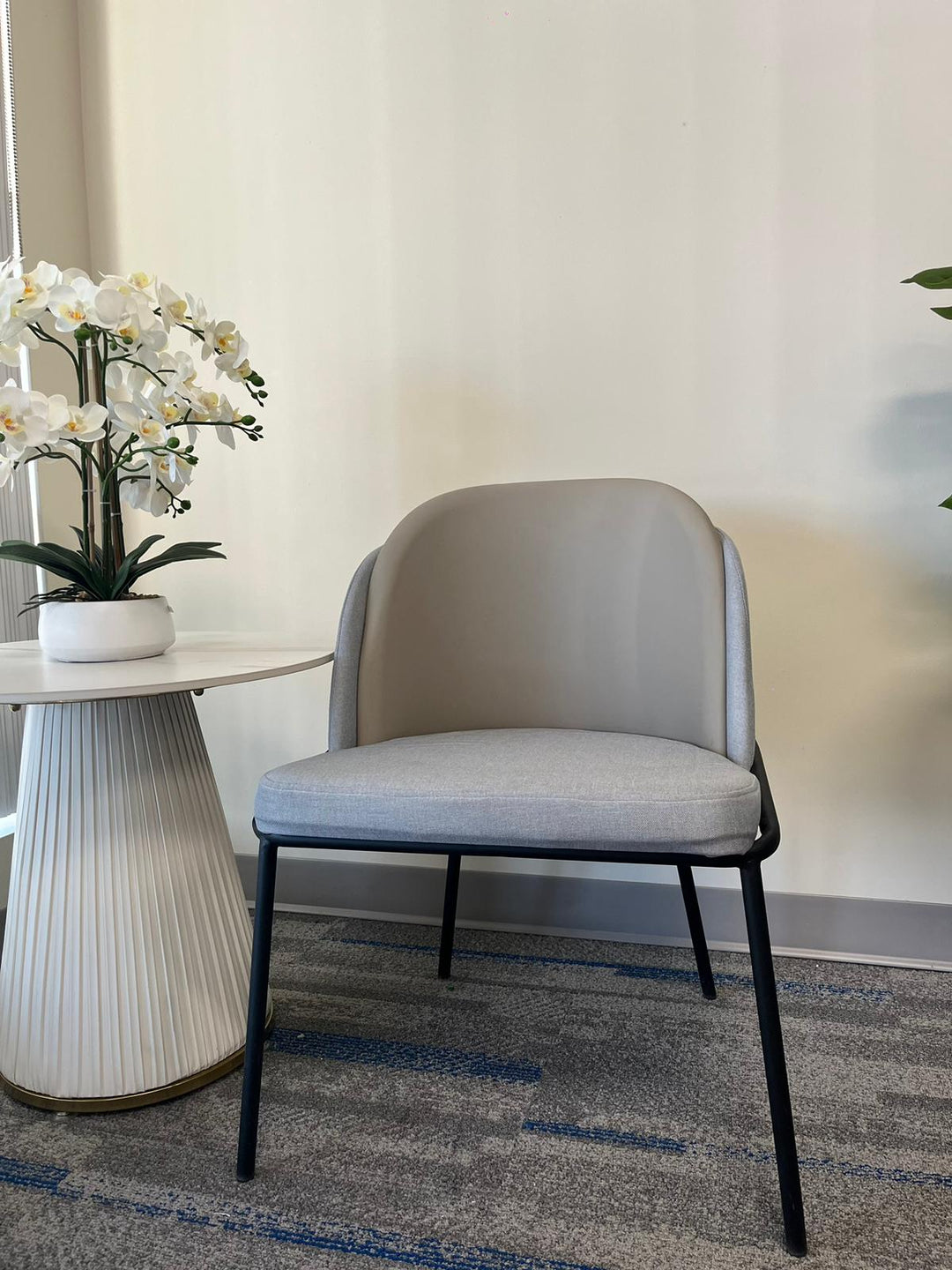 Back view of a modern gray upholstered chair with a black metal frame, often chosen for its contemporary style and comfort. Frequently asked questions about this chair include ‘What are the best chairs for lumbar support in small spaces?’ and ‘How do modern chairs enhance home office setups?