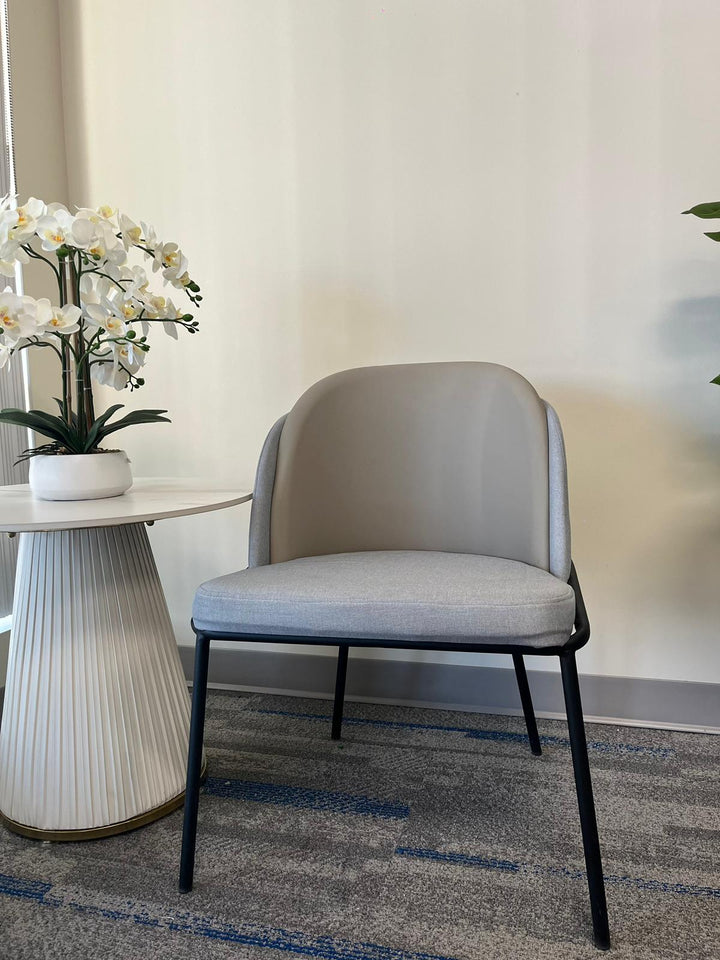 Back view of a modern gray upholstered chair with a black metal frame, often chosen for its contemporary style and comfort. Frequently asked questions about this chair include ‘What are the best chairs for lumbar support in small spaces?’ and ‘How do modern chairs enhance home office setups?