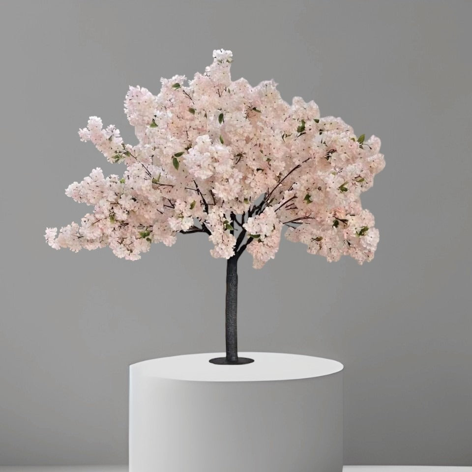 4ft artificial cherry blossom tree in white pink color with dense silk flowers and black textured trunk, standing in a black nursery pot inside a modern living room