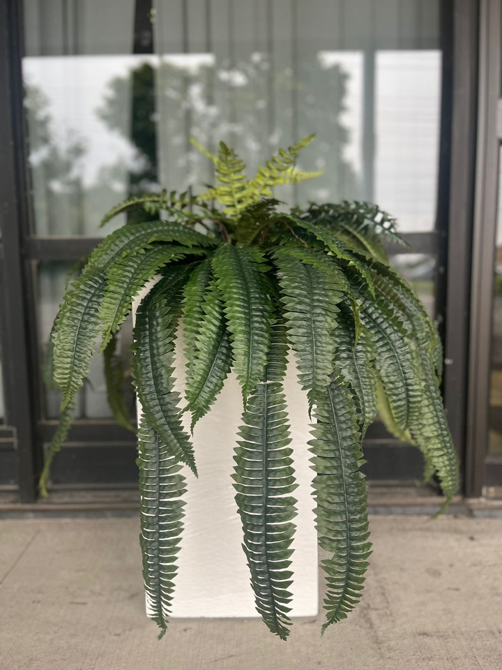 Artificial Boston fern bush placed on tabletop for indoor greenery styling.