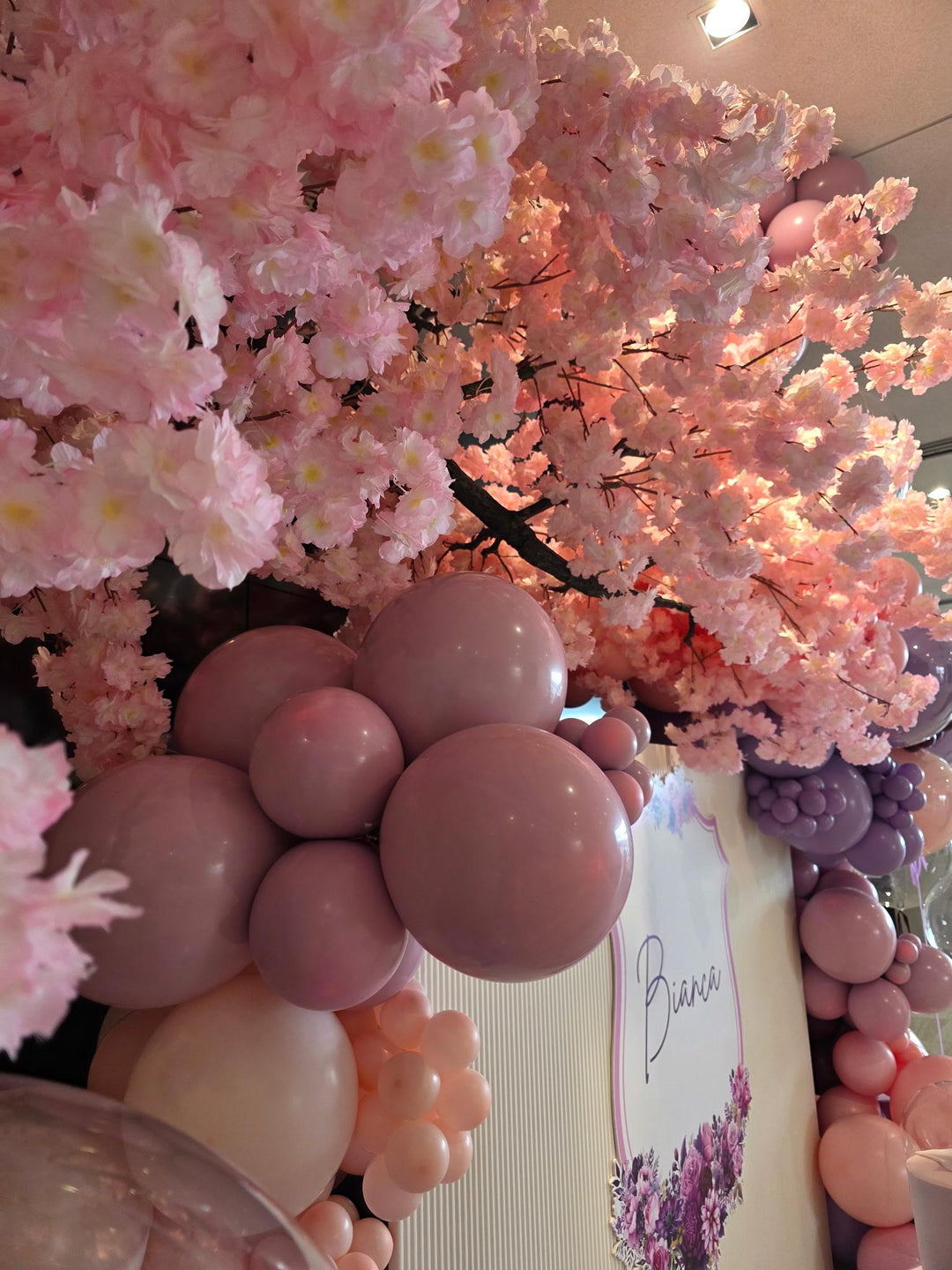 Peach cherry blossom tree  decoration with pink and mauve balloons, a white sign reading &