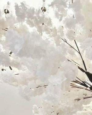 Large white artificial cherry blossom tree  closeup pic decorations with dark branches installed in a bright event hall, with a white runner down 