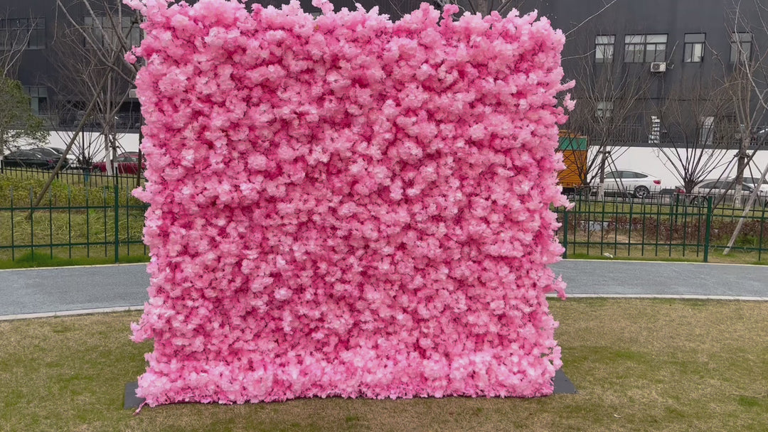 Large pink artificial flower wall backdrop set up outdoors, commonly used for events like weddings, parties, and photoshoots. Is this flower wall backdrop weather-resistant? How easy is it to assemble and transport? Can it be customized in other colors?