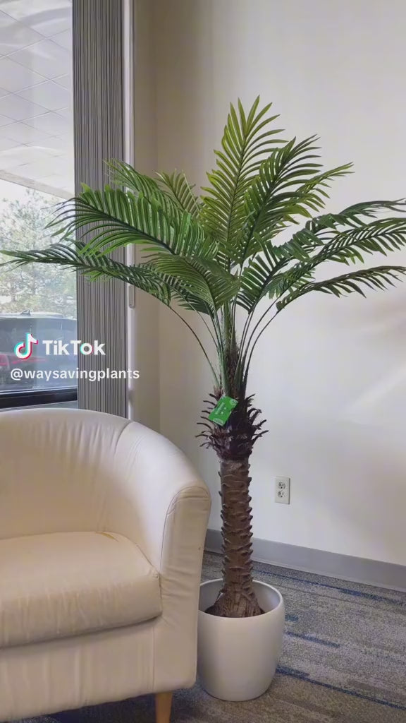 Realistic artificial palm tree placed next to a beige chair, bringing natural vibes to any interior design space.