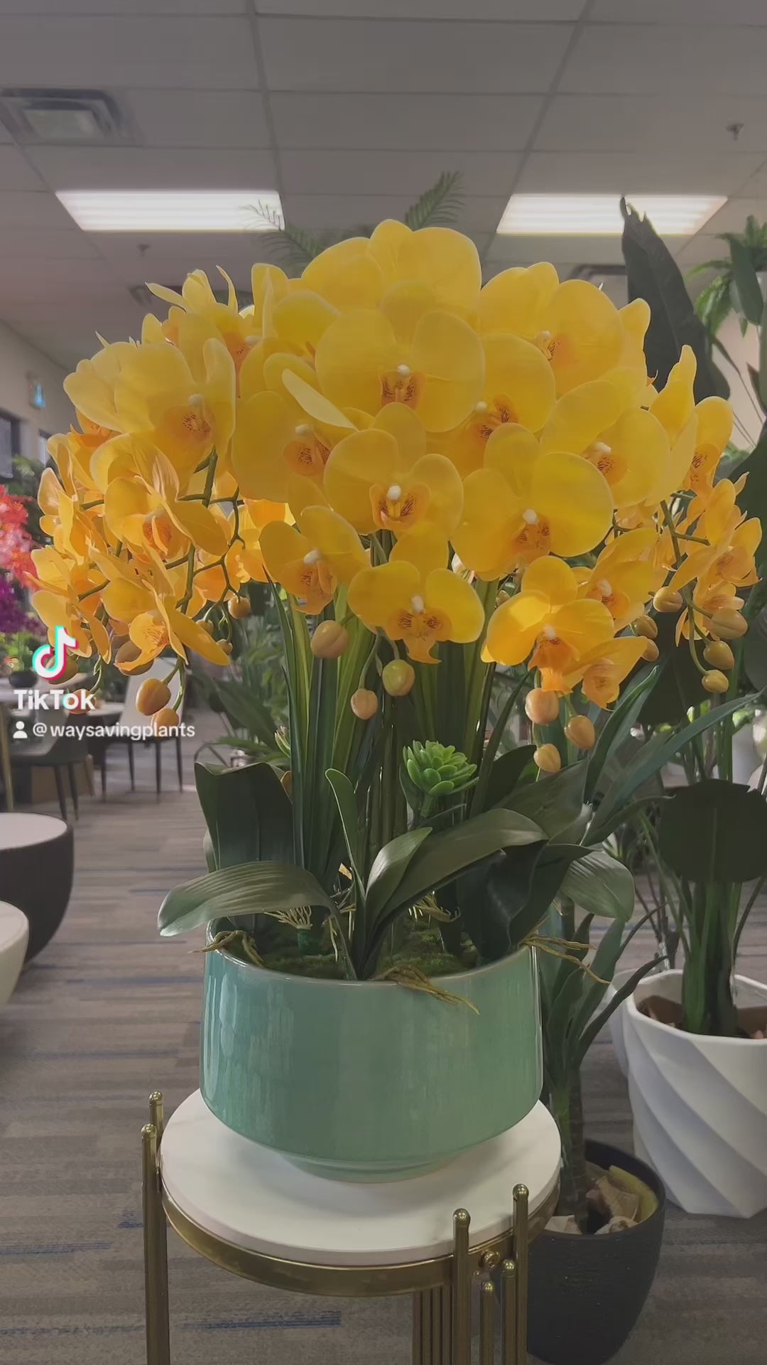 A vibrant arrangement of artificial yellow orchids with realistic petals and buds, displayed in a white ceramic pot. How can I keep artificial flowers looking fresh over time?
