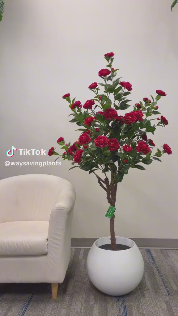 Artificial red flowers in a modern white planter, ideal for adding a vibrant touch to indoor spaces such as living rooms or offices