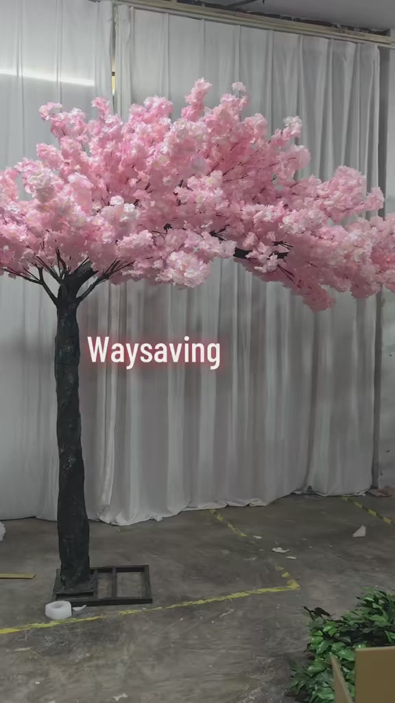 Artificial cherry blossom tree with pink flowers, perfectly placed amidst a lavishly decorated wedding venue featuring pink floral arrangements and cascading fairy lights. Can this artificial tree be customized to match different event themes?