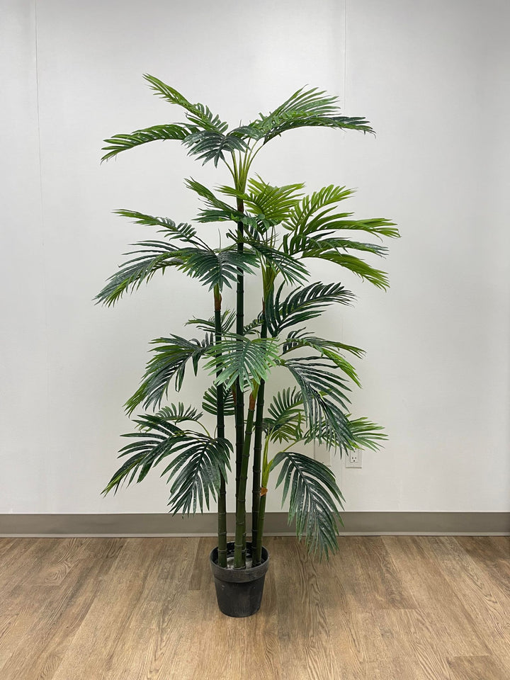High-quality artificial palm tree in a black planter, placed on a wooden floor against a minimalist white wall, perfect for indoor office or home décor.