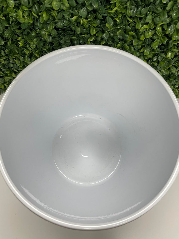 Top-down view of a glossy white ceramic planter, showcasing its smooth interior. The background features green artificial foliage, enhancing the natural aesthetic.