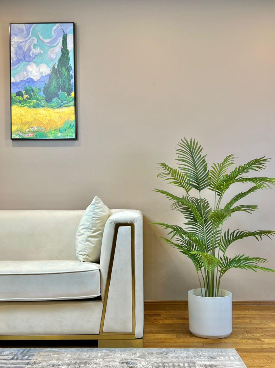Elegant living room setting featuring a lush green palm plant in a black pot beside a modern white sofa with gold accents.