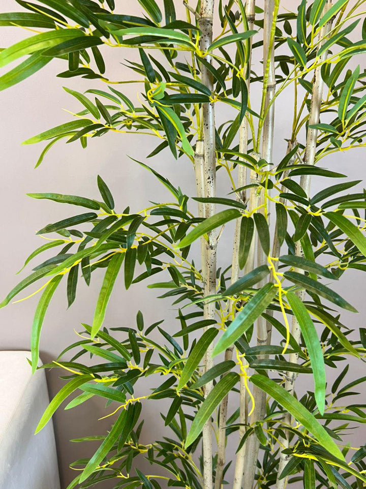 Close-up view of a realistic artificial bamboo plant with detailed green leaves and textured stems, ideal for indoor decor and adding a touch of natural beauty to any space
