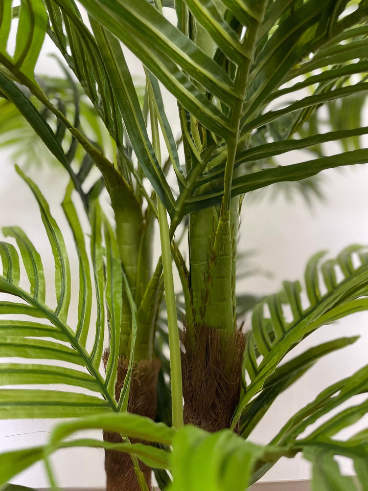 Close-up view of green palm tree fronds showcasing the detailed leaf structure of an artificial palm plant.
