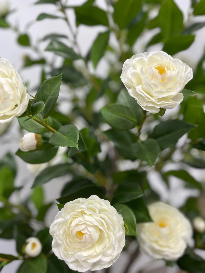 Artificial white flowers with lush green leaves, perfect for elegant indoor decoration in homes or offices.