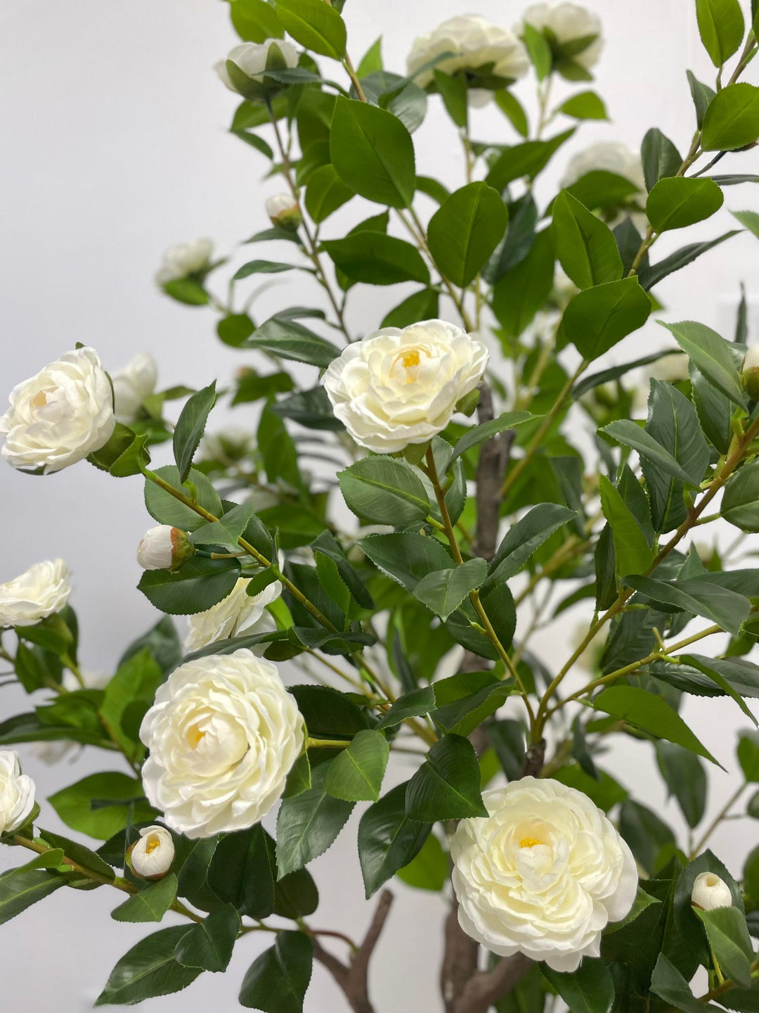 Artificial white flowers with lush green leaves, perfect for elegant indoor decoration in homes or offices.