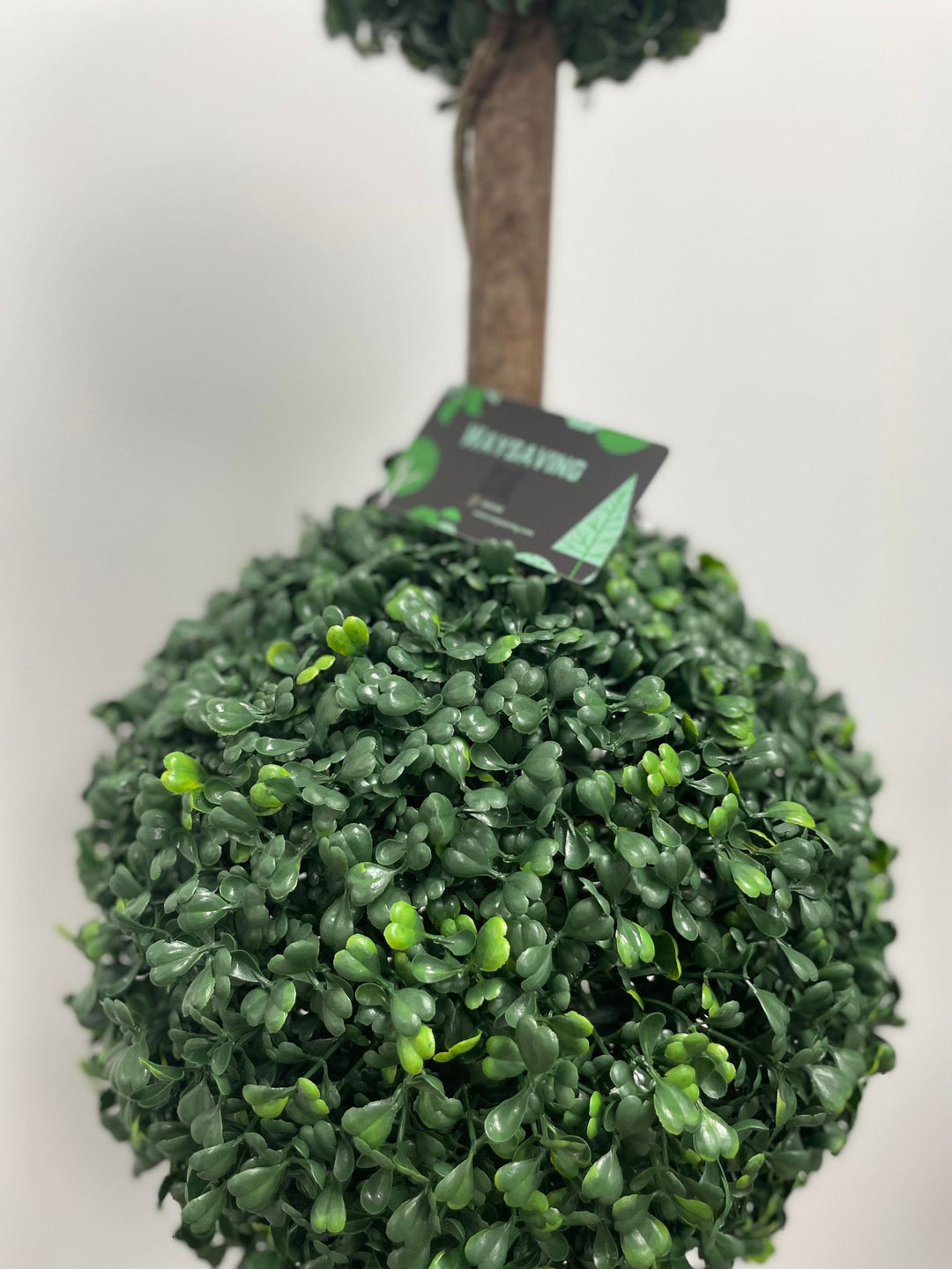 Close-up of a lifelike artificial topiary ball, featuring dense green foliage, perfect for indoor or outdoor decor to add a touch of natural elegance.