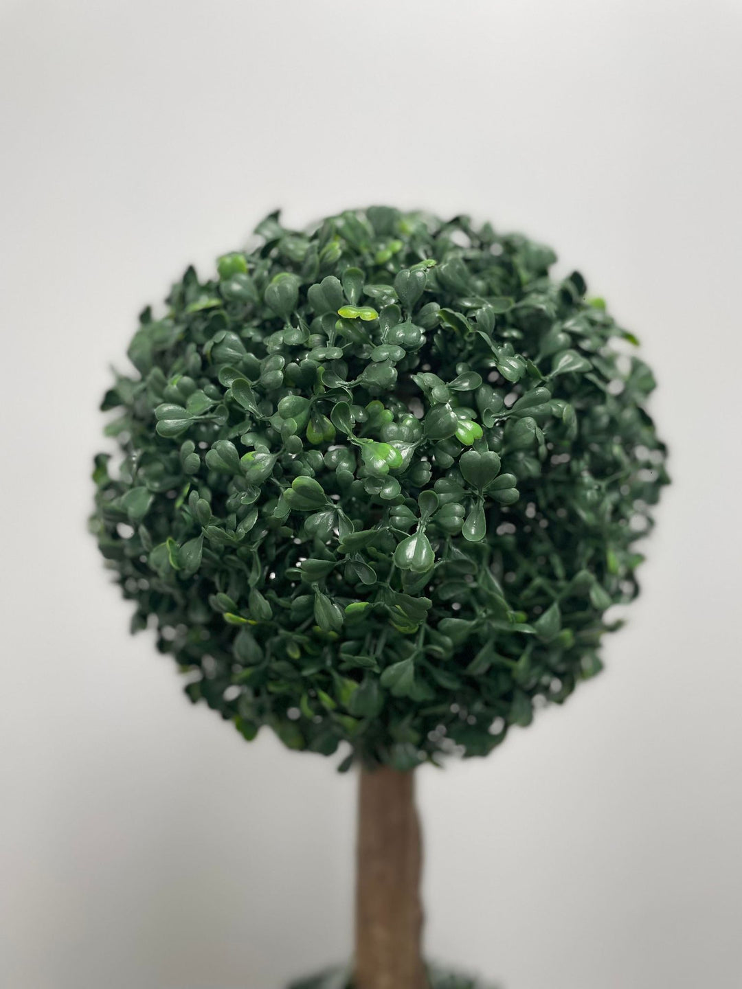 Close-up of a lifelike artificial topiary ball, featuring dense green foliage, perfect for indoor or outdoor decor to add a touch of natural elegance.