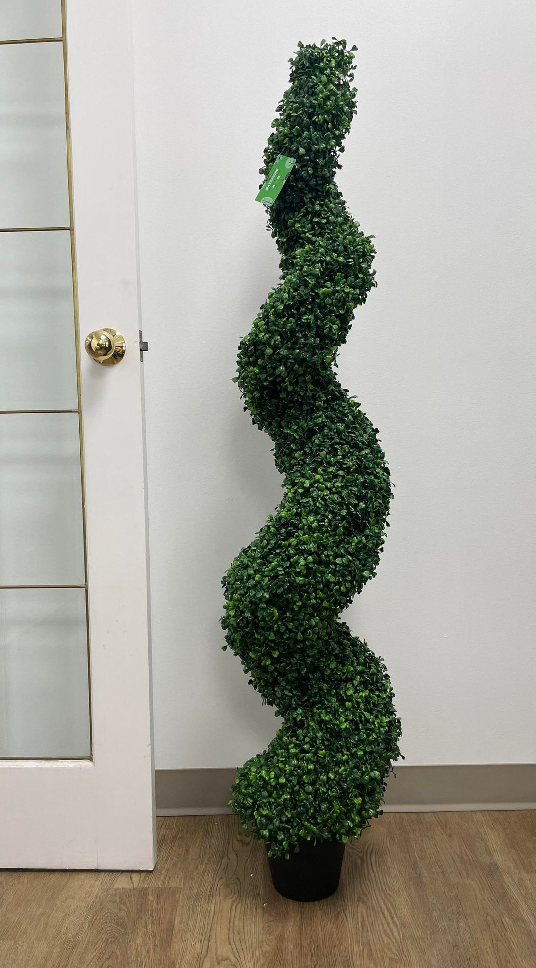 Artificial spiral boxwood topiary beside a modern beige door, perfect for minimalist home or office décor.