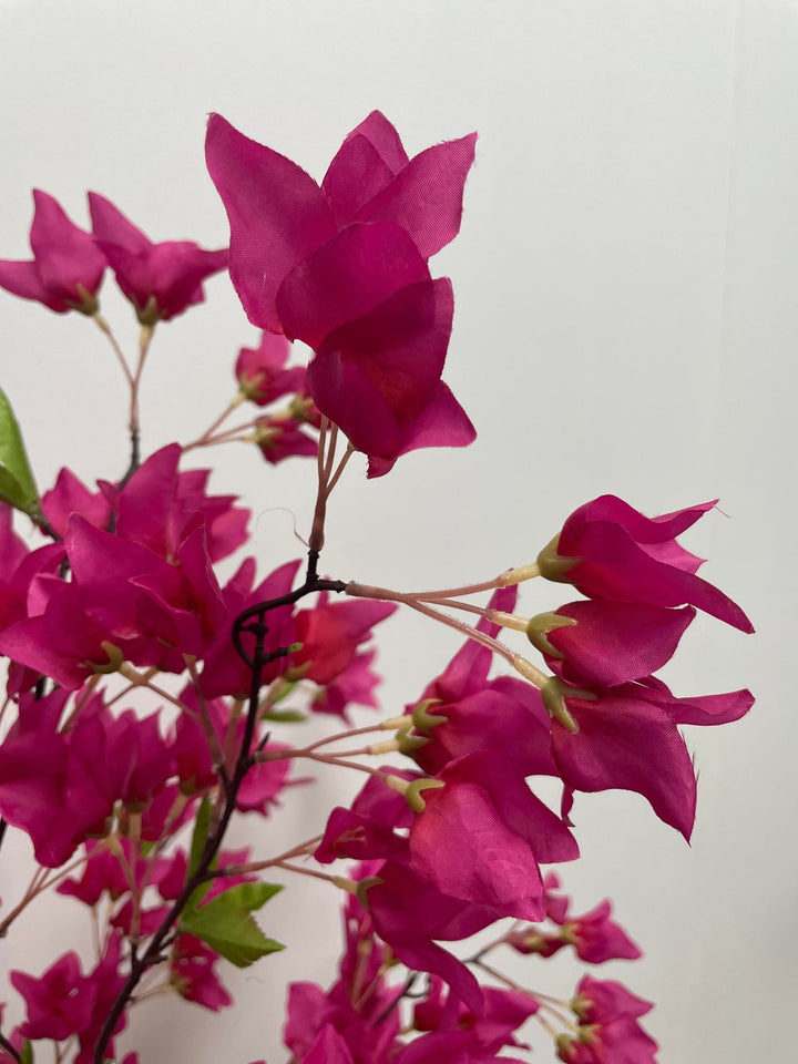 Close-up of artificial pink flowers on a branch with a soft, blurred background, highlighting the vibrant petals and delicate structure