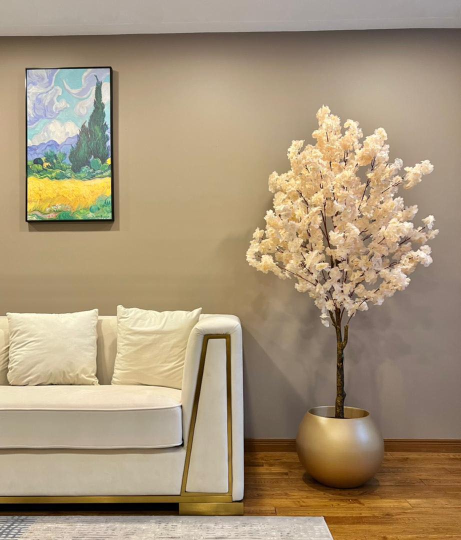 Elegant artificial cherry blossom tree in a gold planter, adding a luxurious and serene touch to modern living spaces.