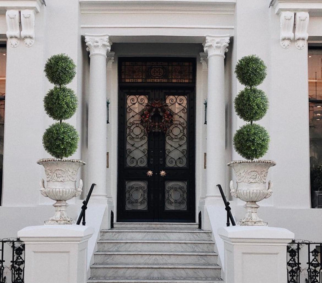 entrance featuring decorative triple-ball topiary plants in ornate white urns, perfect for enhancing curb appeal and adding a sophisticated touch to your home’s exterior.
