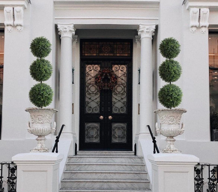 entrance featuring decorative triple-ball topiary plants in ornate white urns, perfect for enhancing curb appeal and adding a sophisticated touch to your home’s exterior.