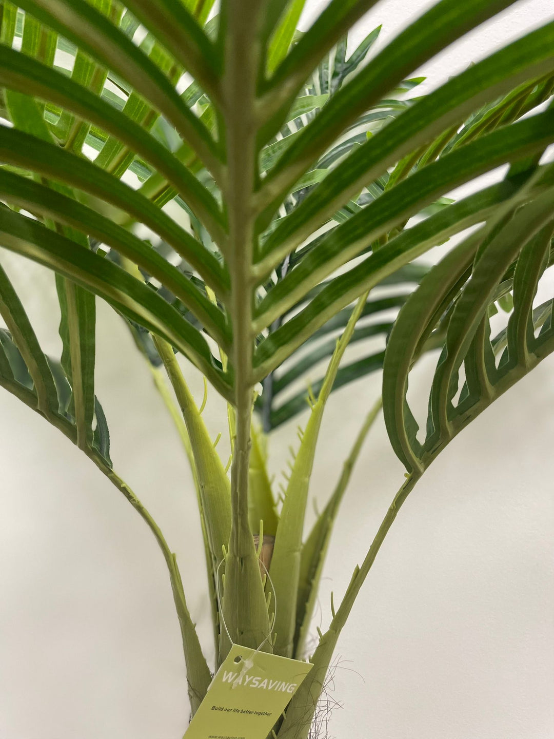 Close-up view of green palm tree fronds showcasing the detailed leaf structure of an artificial palm plant.