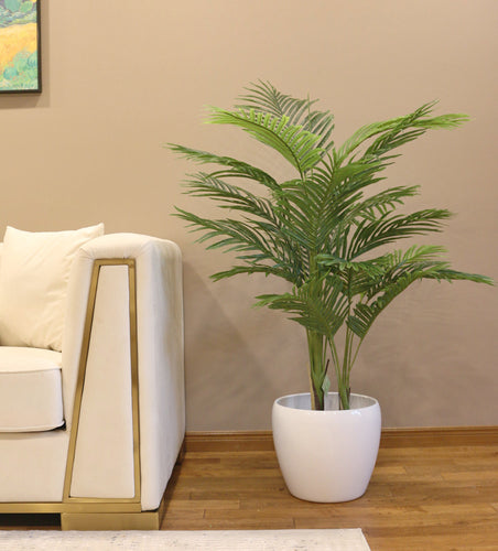 4.3ft artificial palm plant in a modern white ceramic pot, placed beside a luxurious white sofa with gold accents, creating a chic and contemporary living room decor.