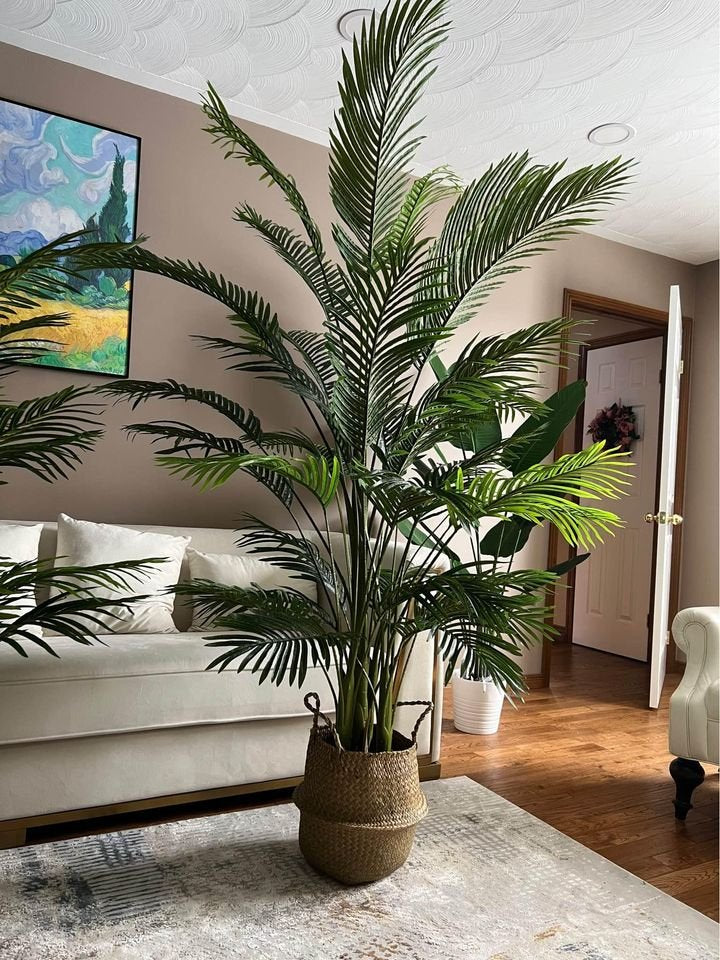A large artificial palm tree in a woven basket planter is placed in a living room, adding a tropical touch to the space.