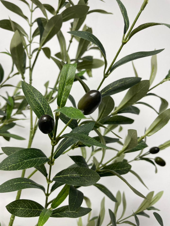 Close-up view of the artificial olive tree's leaves and small dark olives, showing the detailed texture and realistic design of the foliage against a neutral background