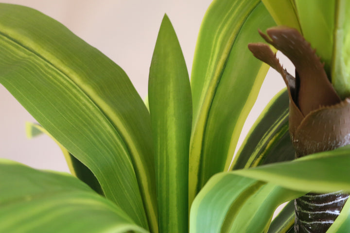 Close-up of vibrant green artificial plant leaves with realistic texture and natural detailing, ideal for home or office decor.