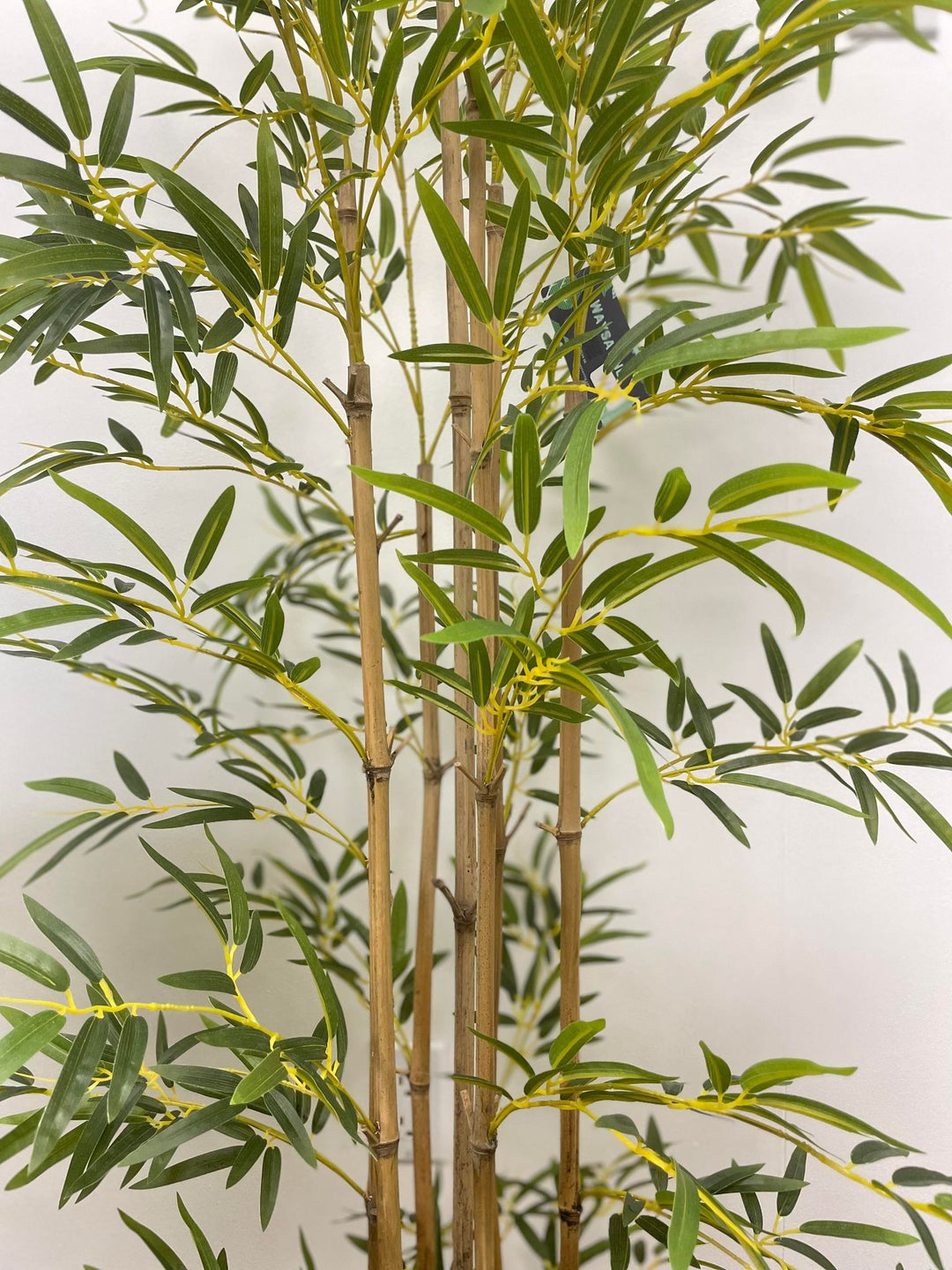 Close-up view of artificial bamboo plant with lifelike green leaves and detailed stalks, ideal for enhancing home or office decor with a touch of nature