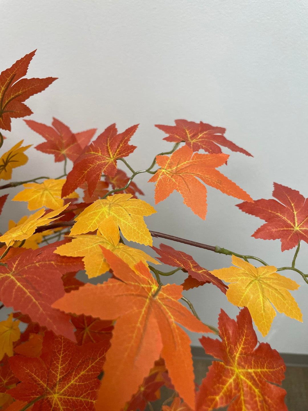 Close-up of artificial maple leaves with defined shape and vibrant yellow and orange colors.