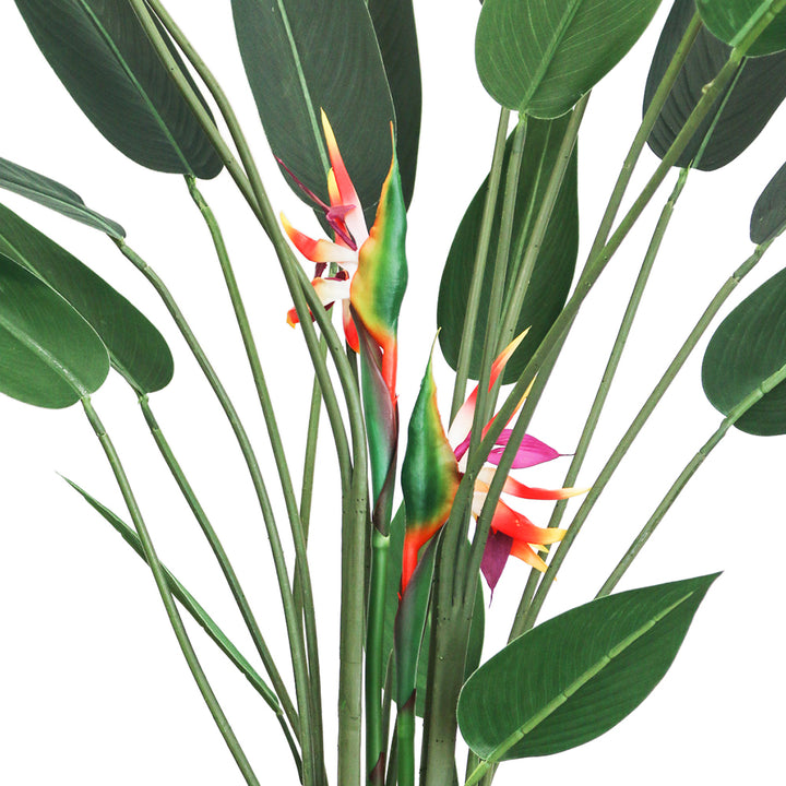 Close-up view of an artificial Bird of Paradise plant showing the vibrant orange and yellow flowers nestled among tall green stems and large, glossy green leaves