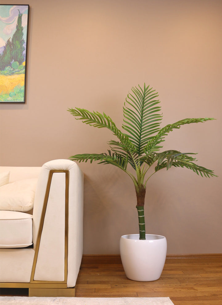 Small artificial palm tree placed in a decorative patterned vase, ideal for adding greenery to any room.